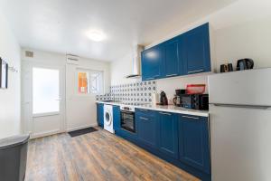 a kitchen with blue cabinets and a white refrigerator at Appart rénové 3 personnes Proche Citadelle in Besançon +11 photos