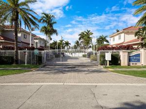 Una puerta en un camino de entrada con palmeras y casas. en Santa Barbara Villa, en Pompano Beach