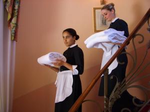 a woman standing on a staircase holding towels at Villa Abbazia Relais & Chateaux in Follina