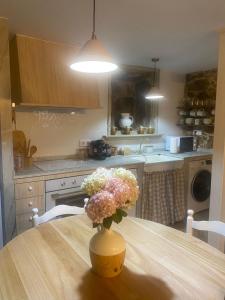 a kitchen with a wooden table with a vase of flowers at O Fogar de Juan in Boiro