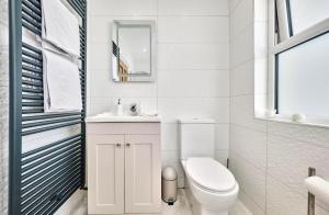 Un baño blanco con inodoro y lavabo. en Portstewart Bungalow, The Open, en Portstewart 24 fotos más