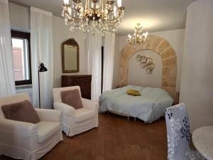 a bedroom with a bed and two chairs and a chandelier at Suite "La Finestra su Alghero" in Alghero