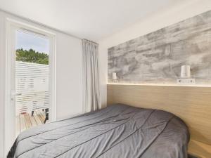 Un dormitorio con una cama al lado de una ventana. en Joli chalet pour 6, résidence avec piscine, en La Parée Preneau 29 fotos más