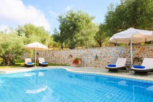 - une piscine avec 2 chaises longues et des parasols dans l'établissement Villa Selini at Sunset Villas, à Skiathos Chora