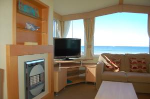 a living room with a fireplace and a television at Premier Caravan F22 at Neptune Park in Tywyn