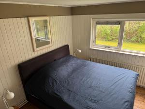 Un dormitorio con una cama con edredón azul y dos ventanas. en Beach Hangout Hygge, en Den Burg