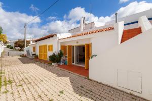 ein weißes Haus mit gelben Türen und einer steinernen Einfahrt in der Unterkunft Beco Luz Studio in Luz