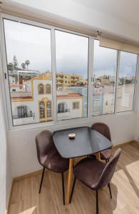 a table and two chairs in a room with windows at O Quintal Guesthouse in Carvoeiro