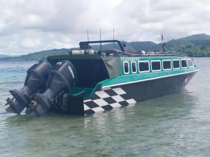 un bateau à damiers est assis dans l'eau dans l'établissement Raja Ampat sea transport, à Pulau Saonek-kecil