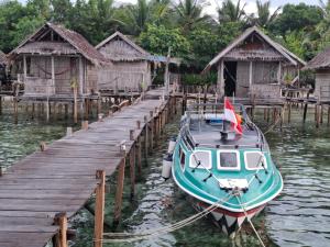 un bateau est amarré à un quai avec des maisons dans l'établissement Raja Ampat sea transport, à Pulau Saonek-kecil