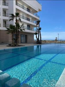 a swimming pool in front of a building with palm trees at Charmant appartement à Anfa in Casablanca