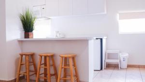 a kitchen with three wooden stools under a counter at Boulevard Park IV 106 in Mayaguez
