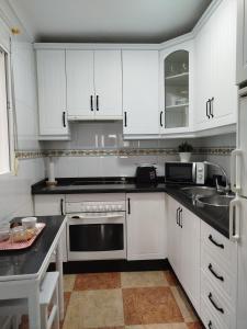 a kitchen with white cabinets and a sink at Casa Lucía - Caminito del rey in Valle de Abdalagís