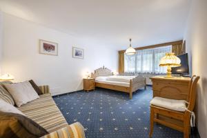 a bedroom with a bed and a couch and a tv at Panorama Apartments Walter in Ortisei