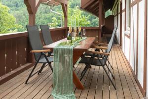 a wooden table on a porch with chairs and wine bottles at Haus Nilson I klimatisierte Ferienwohnung in Gengenbach