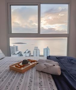 ein Bett mit Tablett und großem Fenster in der Unterkunft Vista Mar 29º - Melhor Localização em Vila Velha in Vila Velha