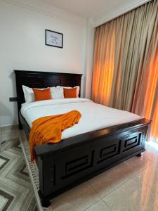 a bedroom with a bed with an orange blanket on it at Idyllic nest ,studio apartment in Nairobi +14 photos