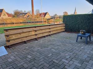 a wooden bench with a table on a brick patio at Sweltsje in Sprong