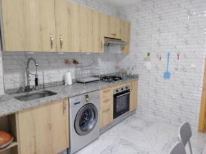 a kitchen with a sink and a washing machine at Aeroport Tissir Appartement in Nouaceur