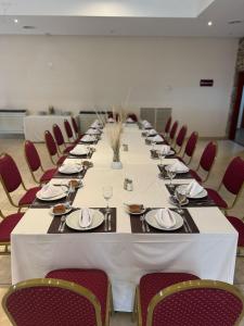 a long table in a room with red chairs at Hotel Sol del Añelo in Añelo