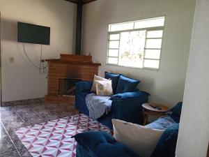 a living room with two blue couches and a television at Canto dos Pássaros- Casa de campo em Gonçalves in Gonçalves