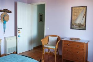 a bedroom with a dresser and a chair next to a door at Vereniki Andros guesthouse in Batsi