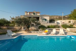 a swimming pool with chairs and a house at Villa Pax in Kastel Stafilic