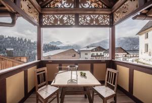 Una mesa y sillas en una habitación con una ventana grande. en Ciasa Somuer, en San Vigilio Di Marebbe