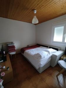a bedroom with a white bed and a wooden ceiling at A Casiña de Rande in Redondela