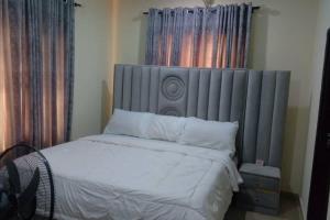 a bedroom with a large bed with a gray headboard at 2 Bed-Sleeps 4-Free Parking-AirCon-3 in Benin City
