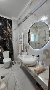 a white bathroom with a sink and a mirror at Catherine's Beachfront Apartment by Optimum Link in Paralia Katerinis +29 photos