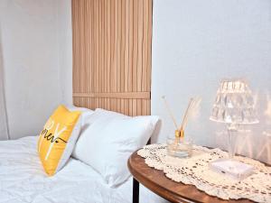 a bed with a table with a yellow pillow and a lamp at Private House Good Stay Samdeok in Daegu +24 photos