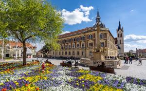 a large building with a fountain and flowers in front of it at Gold & Green Apartment in Keszthely
