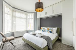 a bedroom with a large bed and a chair at Spacious 3BR Home with Garden & Parking, Ilford in Seven Kings