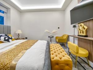 a bedroom with a large bed and yellow chairs at The Spa Nook with Hot Tub, Sauna and Room for 8 in East Barnet