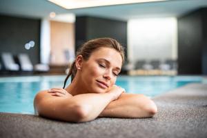 a woman laying in a swimming pool at Domaine Des Hautes Fagnes in Ovifat
