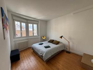 Un dormitorio con una cama y una lámpara. en Chrysalide au cœur du Touquet., en Le Touquet-Paris-Plage