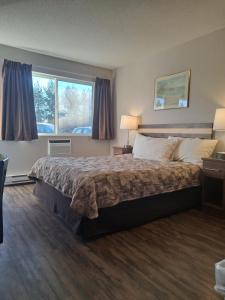 a hotel room with a bed and a window at Bon Voyage Inn in Prince George