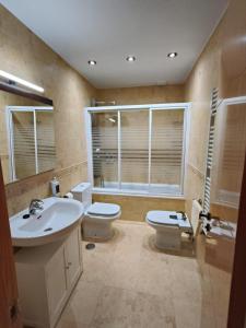 a bathroom with a sink and a toilet and a window at Casa Buenavista in Las Navas del Marqués