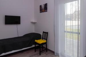 a bedroom with a bed and a chair and a television at Milla Apartman Szeged in Szeged