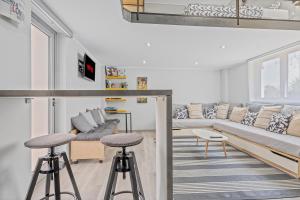 a living room with a couch and two bar stools at Kyma Holiday Loft in Artemida