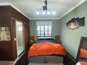 a bedroom with a bed with an orange blanket at Chácara Itaqueri Ambar in São Pedro
