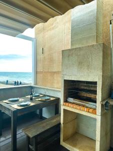 a pizza oven with a table and a view of the beach at MARESIA APART T0 - Praia do Furadouro in Ovar