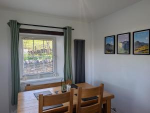 a dining room with a wooden table and a window at Cosy country cottage with log fireplace and views in Kendal