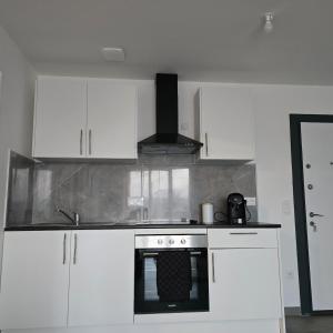 a kitchen with white cabinets and an oven at Urban Zen - Freneuse in Freneuse +1 photo