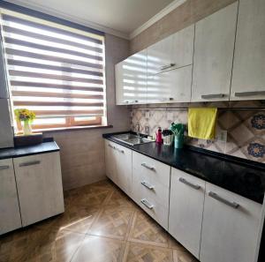una cucina con mobili bianchi e un piano di lavoro nero di 2х-ком Люкс Желтоксан 20 - 5й этаж Лифта нет извините a Shymkent