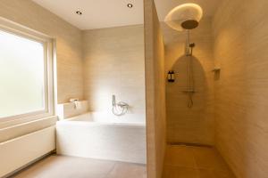 a bathroom with a tub and a shower with a window at Kasteel De Vanenburg in Putten
