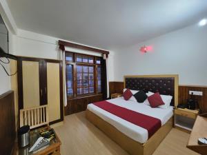 a bedroom with a large bed with red pillows at Kundan Hotel and Restaurant in Manāli +51 photos