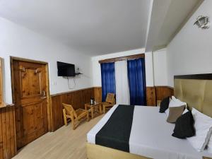 a bedroom with a bed and a table and a television at Kundan Hotel and Restaurant in Manāli