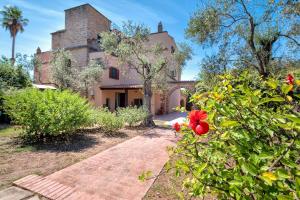 a house with a red flower in front of it at Villa con Piscina Alghero in Alghero